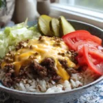 Bowl of cheeseburger rice with beef, cheese, lettuce, and pickles
