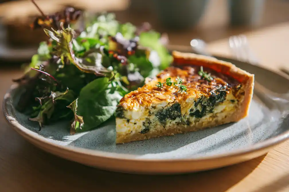 A slice of spinach and feta quiche served with salad