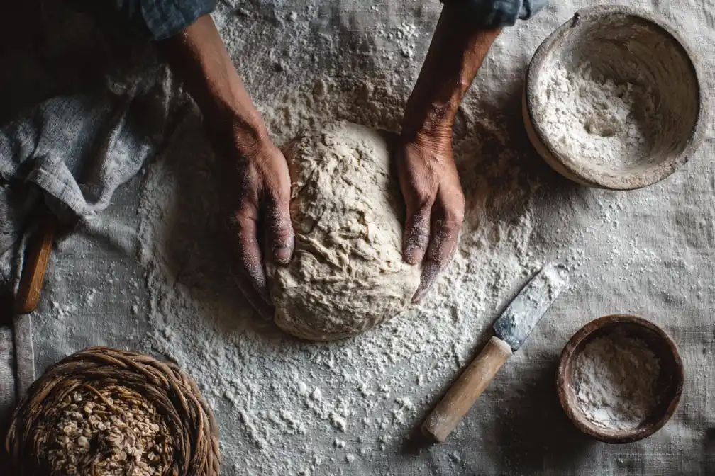 Hands shaping sourdough dough on a floured surface during stretch and fold