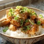 A bowl of slow cooker hot honey chicken with rice and toppings