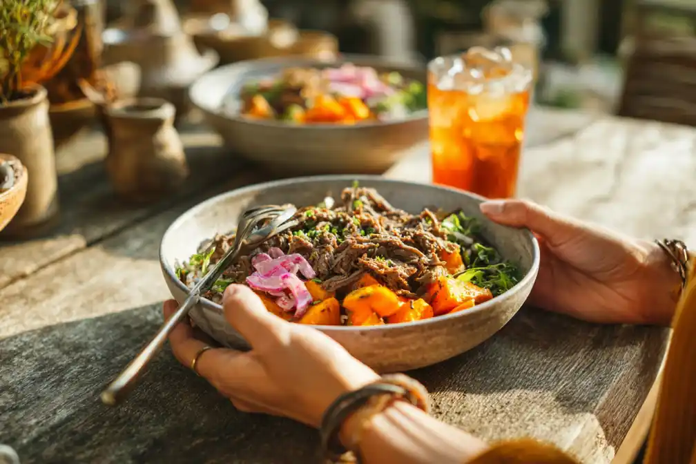 Hands serving a beef and veggie power bowl at a family table.